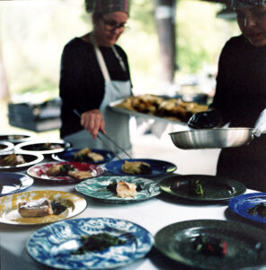 Chefs plating a multi-course meal on colorful ceramic dishes at an outdoor LOCH Winery dinner event